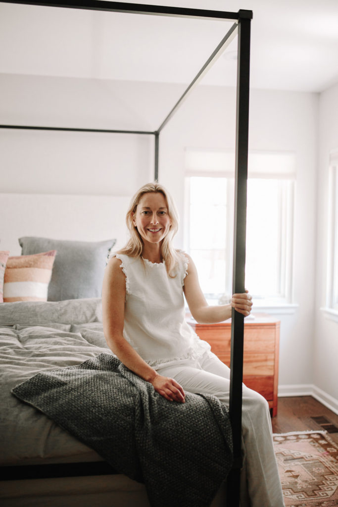 woman sitting on the corner of a bed