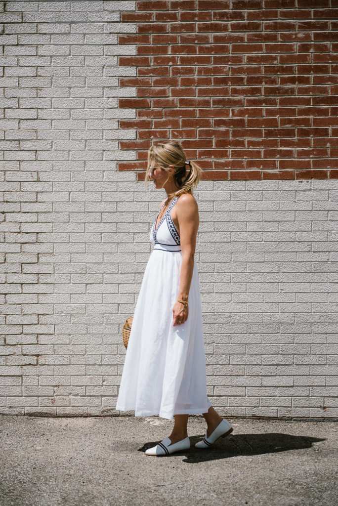 woman walking and wearing a white summer dresses with white flats