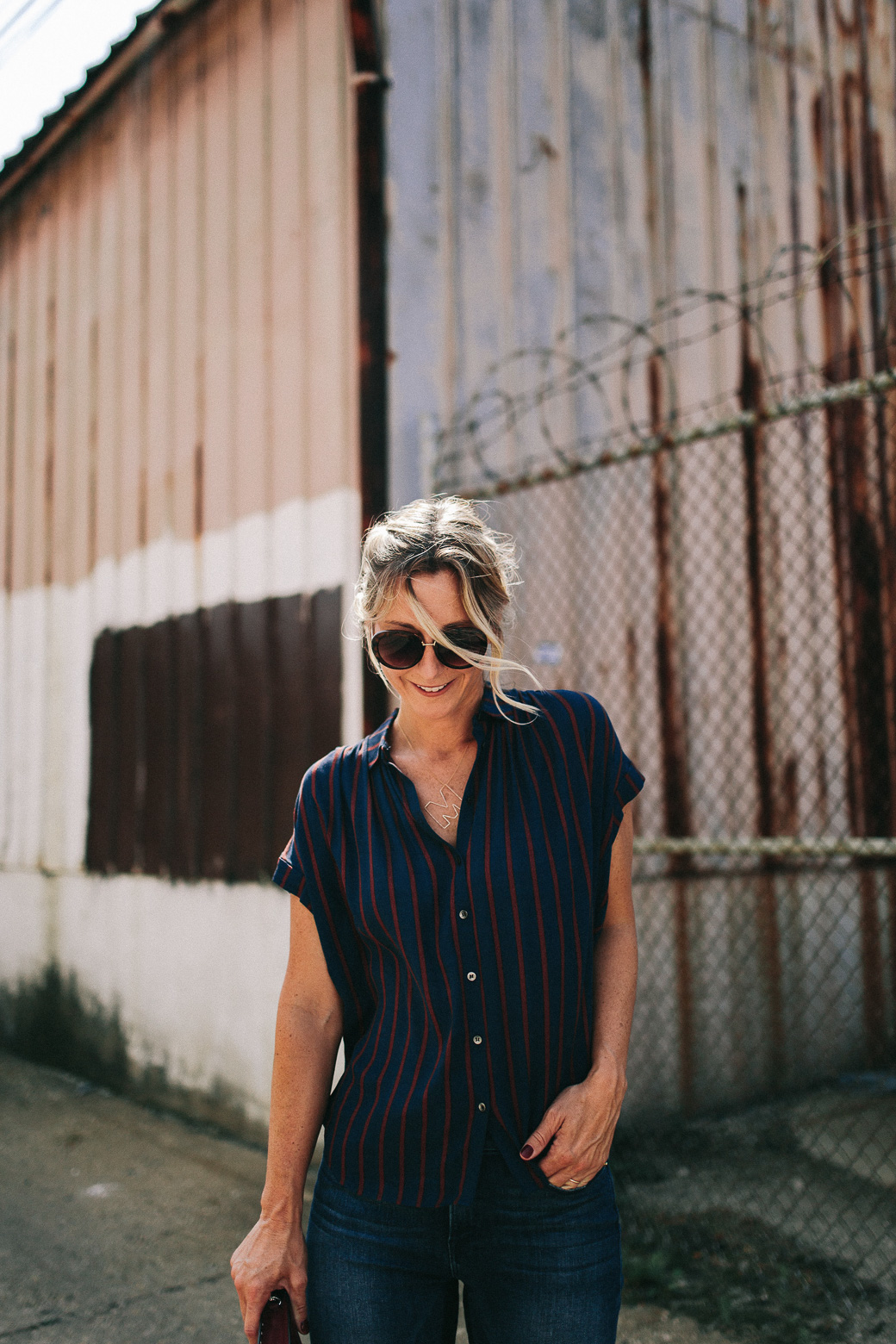 how to pack for Nashville, a girl in shades and stripped shirt smiling at the ground