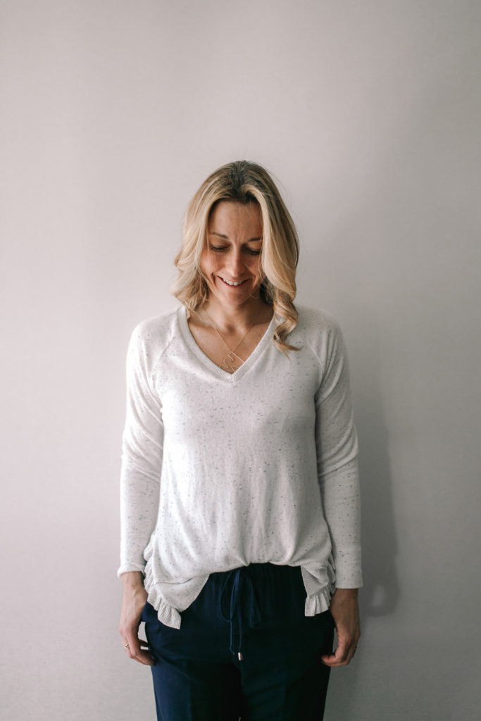 woman wearing loose fitting white and blue speckled sweater with ruffle detail for travel attire
