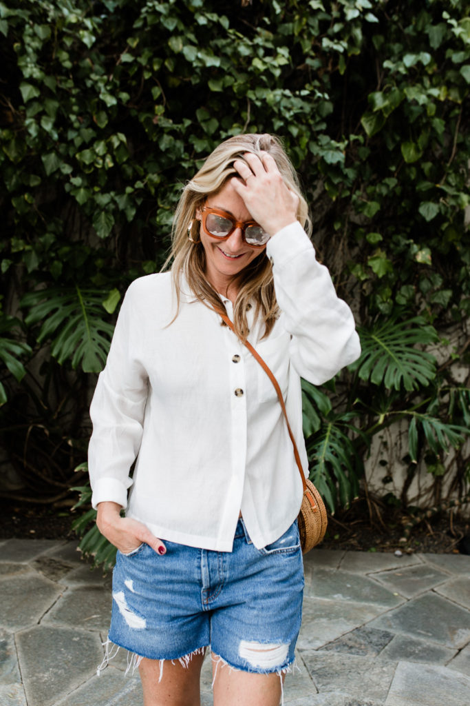 woman smiling and wearing denim shorts and White Essentials for Spring 