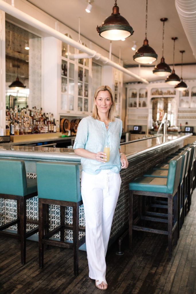 a woman at guildhall brunch with a glass in her hand and an empty bar in the background