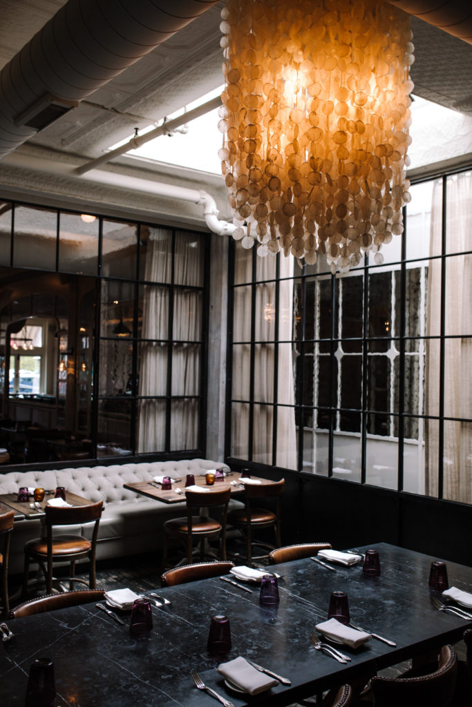 a dining room with dark lighting and a large overhead chandelier