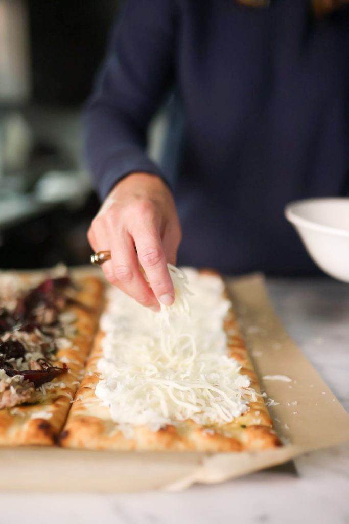 person adding cheese on flatbreads